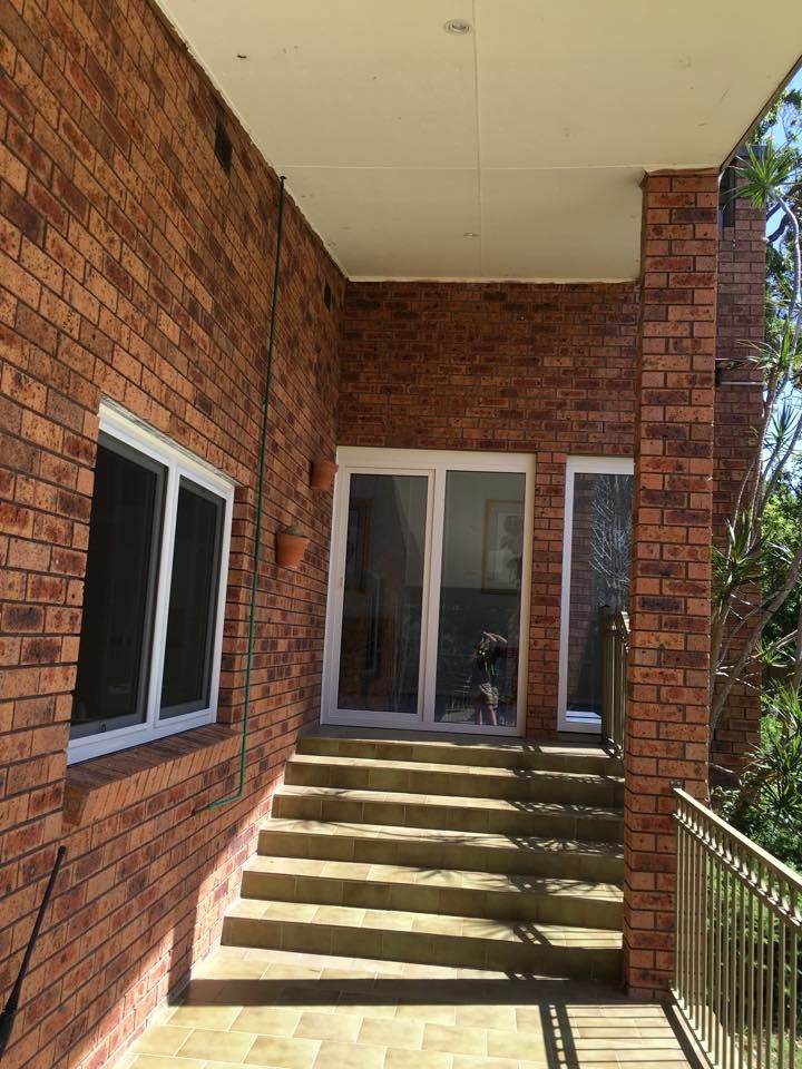 A brick house with stairs leading to a balcony.