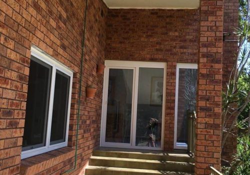 A brick house with stairs leading to a balcony.