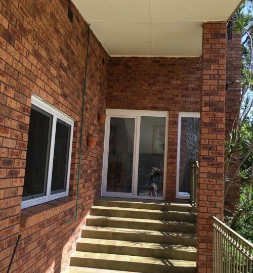 A brick house with stairs leading to a balcony.