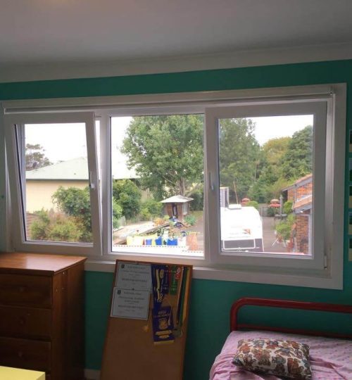 A child's bedroom with a window and a desk.