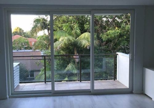 An empty room with wooden floors and a balcony.