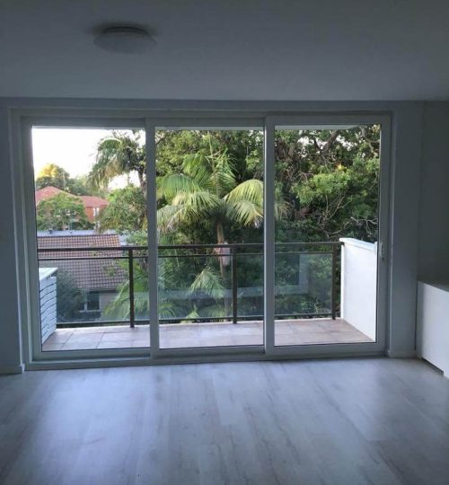 UPVC Sliding and Stacking Doors 3 An empty room with wooden floors and a balcony.