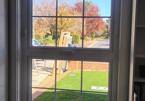 A white UPVC casement window in a room with a grassy yard.