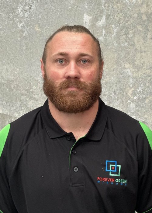 A man with a beard standing in front of a wall.