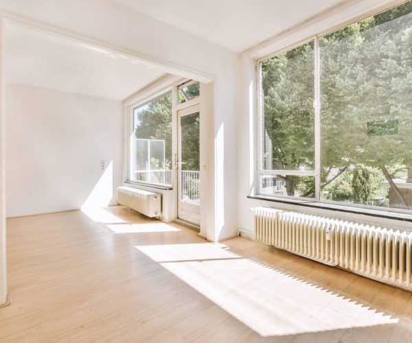 Plastic window and radiator on white wall in empty light room at home